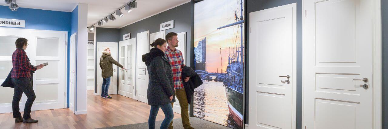 Die A&J Türenausstellung - Hamburgs größte Türenauswahl Menschen schauen sich weiße Profiltüren in der A&J Türenausstellung an